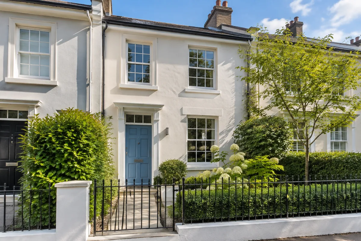 The exterior shot: a white townhouse with a blue door behind a black iron railing. Generated with GPT-Image 2.5; this house does not exist.